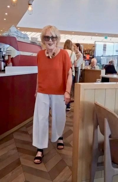 オレンジのトップスに白のワイドパンツを合わせたカフェコーデ