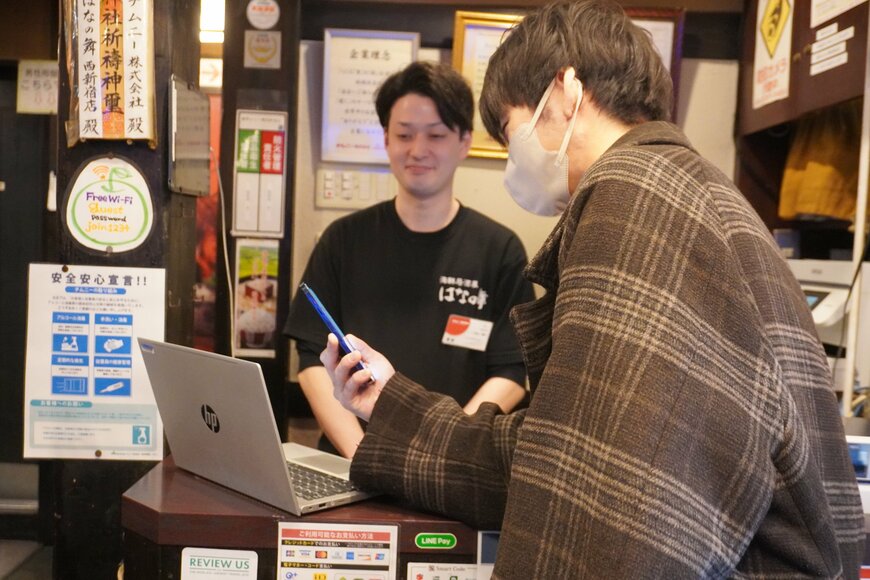 PCの画面をスマホのカメラで読み込む男性の写真