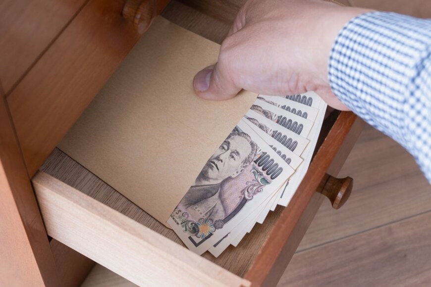 男性が引き出しからお金を出す様子の写真