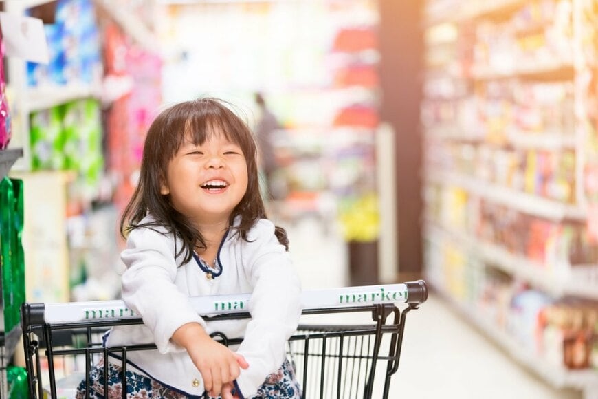 子どもがスーパーのカートに乗っている写真