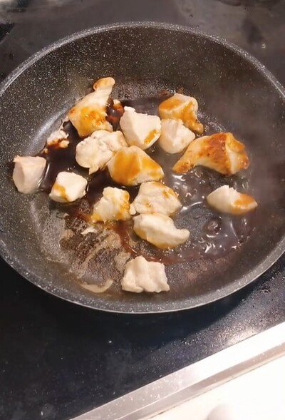 蒸し焼きにした鶏肉にタレを絡める