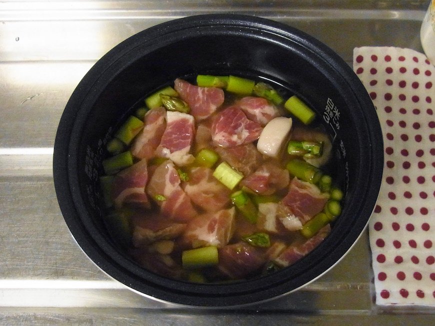 米に醤油とアスパラ、塩豚を入れて炊飯する。