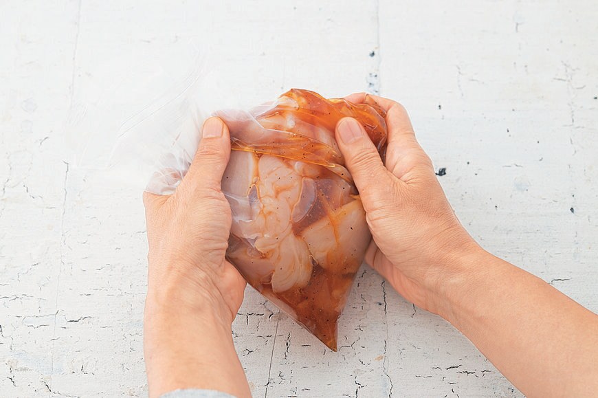 肉や魚などの食材を加える。まんべんなく調味料がいきわたるように袋の上からさらにもんでなじませる。