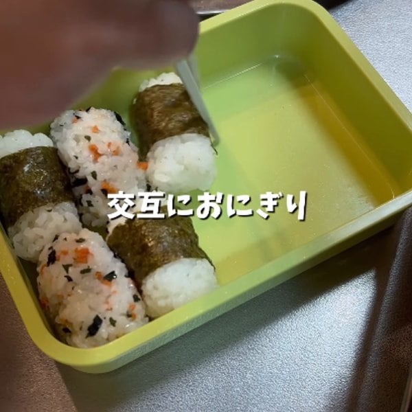交互に詰める「おにぎり弁当」の盛り付けアイデア。唐揚げをぎゅうぎゅうに詰め、断面を見せた色鮮やかなハムエッグで彩る、食欲をそそる見栄え抜群なお弁当術