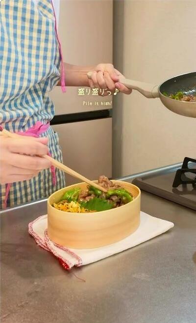 ご飯の上に豚肉とししとうが盛られていくところ