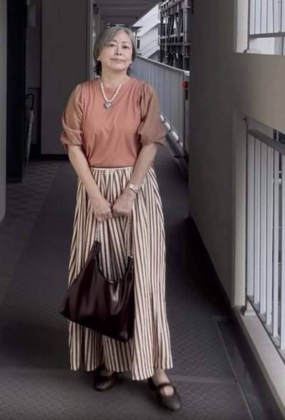 サーモンピンクのトップスとストライプ柄のマキシスカート