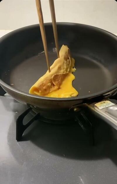 丸いフライパンで巻かれていく卵焼き