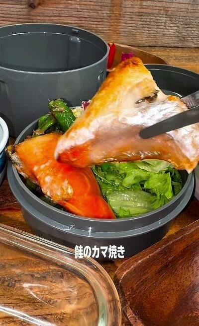 2切れ目の鮭のカマ焼きが、手前に運ばれてくるところ