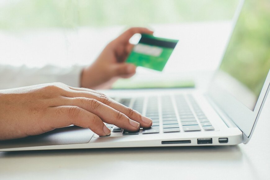 クレジットカードを手に、パソコンを操作している様子。