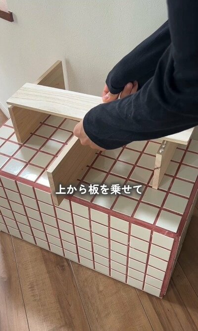 ボンドを塗った板の上に、もう1枚の板を重ねて足で押さえ、圧着させている様子。