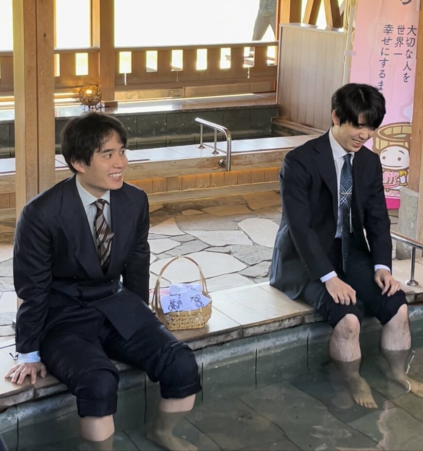 足湯に浸かって笑顔を見せる藤井聡太竜王（右）と佐々木勇気八段