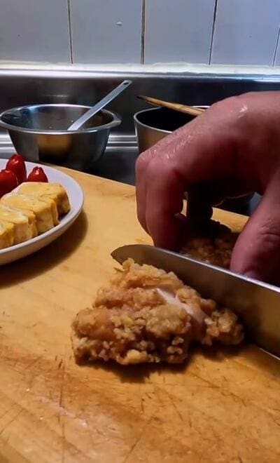 揚がった鶏肉を包丁で切り分ける