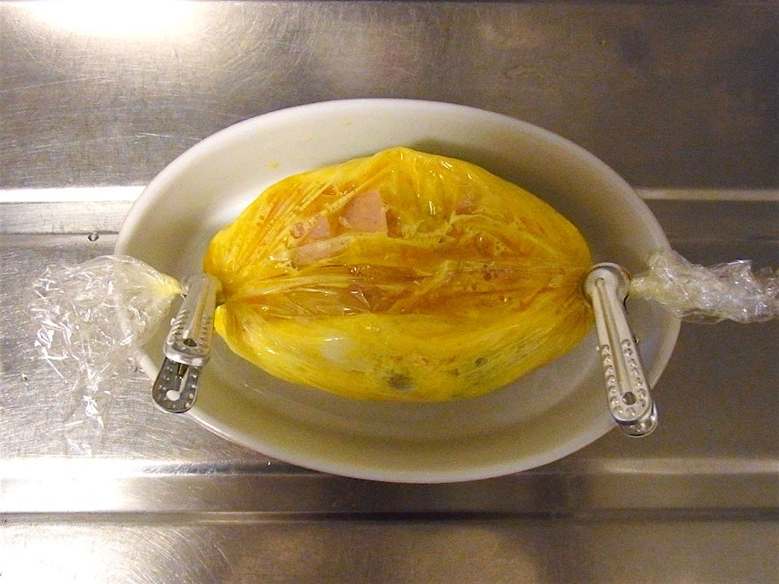 電子レンジで所定の時間熱した後、ラップの端を絞って止め（やけどに気をつけて！）、卵が固まるまで10分ほど置く