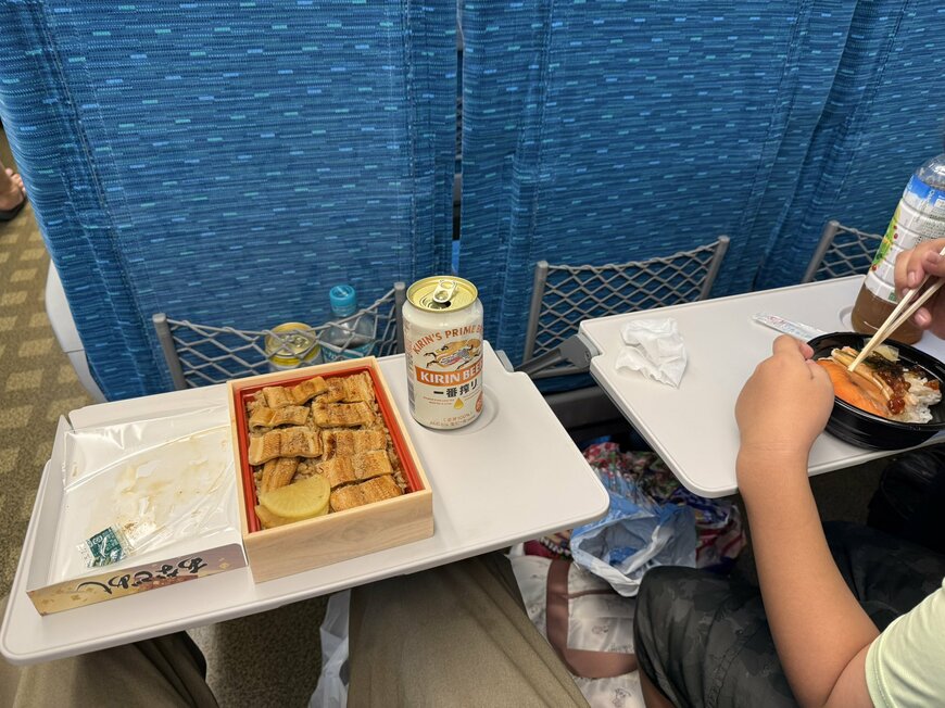 急遽新幹線に乗って駅弁を食べる様子