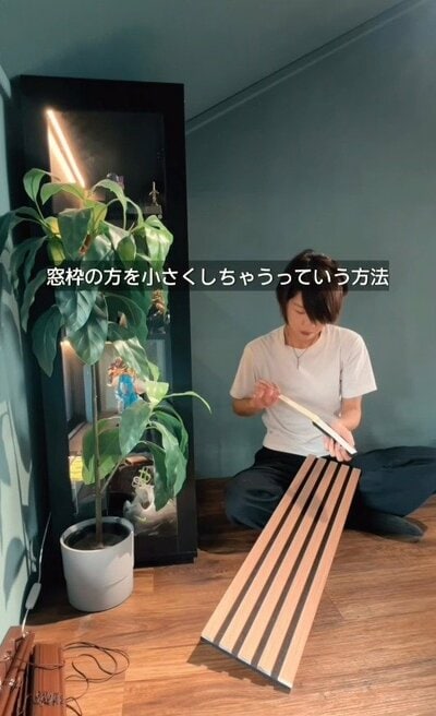 窓枠の方を小さくするというアイデアを思いつき、部材を手に取る様子