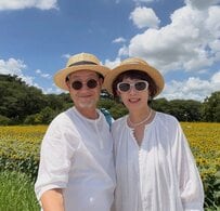 【夏の60代夫婦】ひまわり畑に映える「白コーデ」が素敵！“麦わら帽子と差し色のブルー”が青空にマッチ
