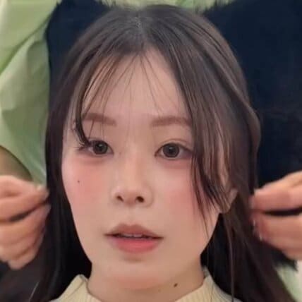 面長で額が広いと悩む女性の顔まわりを施術。前髪の幅を広げつつ長く薄めに作り、サイドの髪が自然に横に流れるように骨格をカバーするプロの技