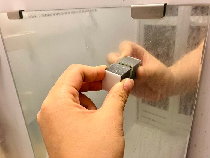 ウロコ取りで鏡をこする様子