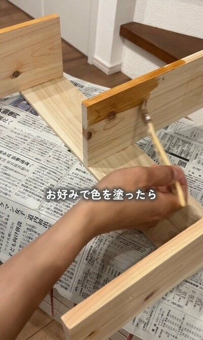 新聞紙を敷いて、棚をお好みのカラーに塗装している様子。