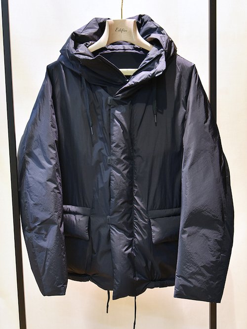 〈テアトラ〉の代名詞的モデルである「スーベニアハンター」のショート丈のダウンバージョン。旅先でお土産を買い漁っても平気な収納量を誇る。ダウンは南極観測隊にも採用される老舗日本ダウンメーカーZANTER社製。暖かいだけでなく、同ブランド史上最軽量のアウター。TEATORA / Souvenir Hunter S/L-EVA ¥110,000（税込み）