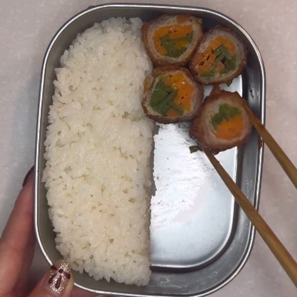 彩り鮮やかな断面で食欲をそそる「肉巻き弁当」がきっちり綺麗に詰まって見栄え抜群で美味しそう！スプーンでブロッコリーを押さえながらおかずの隙間を埋めていくお弁当の詰め方が参考になる