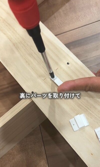 棚の裏側に、壁掛け用のパーツを取り付けている様子。