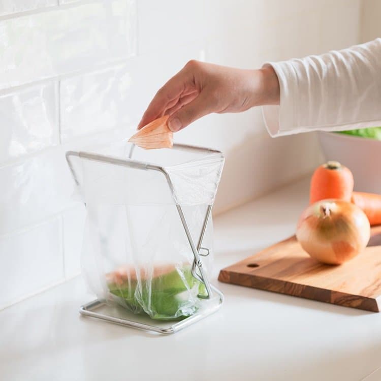 袋をかけたOacs スタンドダストバッグホルダーに野菜くずを入れる手元