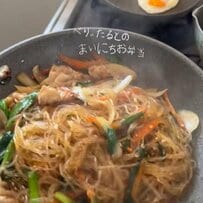 ポリ袋で豚肉に片栗粉を揉み込むひと手間で、自然なとろみがつく調理アイデア。目玉焼きを乗せたチャプチェとおにぎりを合わせた、食欲をそそる夫弁当の実用的な工夫