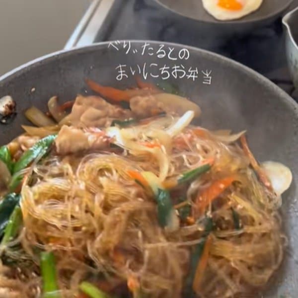 ポリ袋で豚肉に片栗粉を揉み込むひと手間で、自然なとろみがつく調理アイデア。目玉焼きを乗せたチャプチェとおにぎりを合わせた、食欲をそそる夫弁当の実用的な工夫