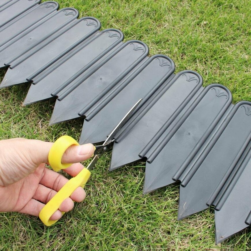 コメリオリジナル商品の土と芝のボーダーシートをはさみで切っている