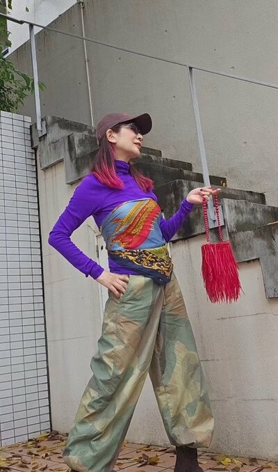 スカーフをビスチェ風に巻いたパープルのトップスとカモフラ柄パンツ