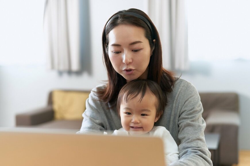子どもを抱えて働く女性の写真
