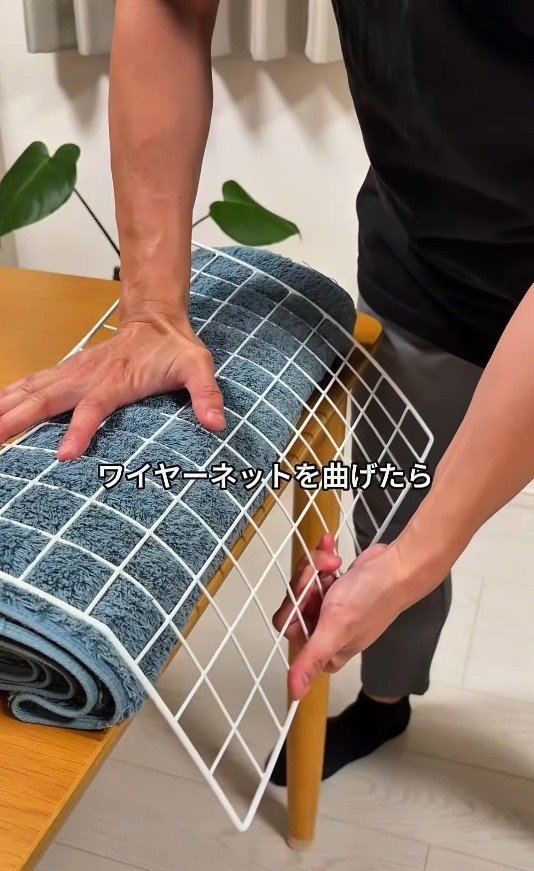 丸めた毛布を使ってワイヤーネットを曲げている様子