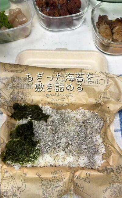 黒とろろ昆布を散らしたご飯に、ちぎった海苔を重ねていくところ