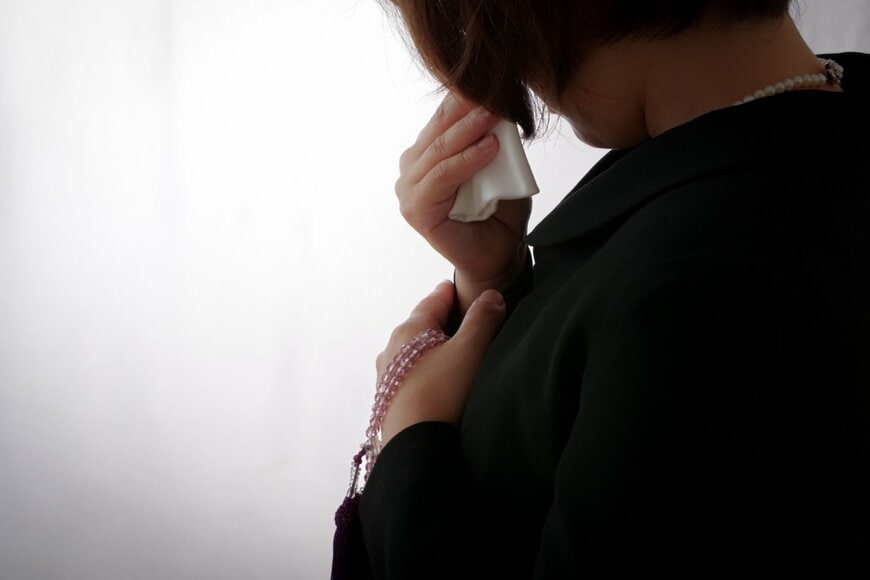 喪服姿の女性が泣いている。
