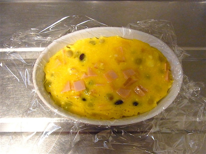 耐熱皿にラップをしき、卵と調味料、具を混ぜ合わせたものを流し入れる
