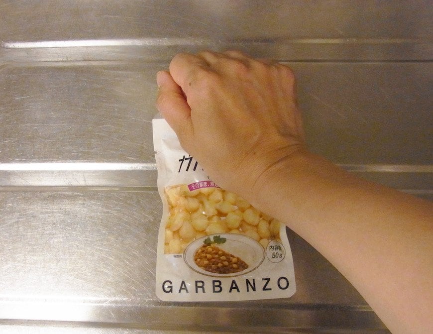 袋の上からひよこ豆を手でつぶす