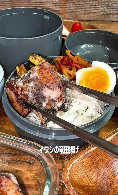 手前のせん切りの上に、イワシの竜田揚げが置かれていくところ