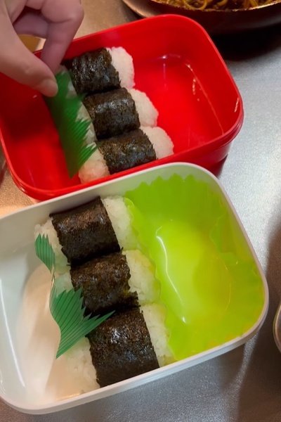 俵おにぎりの詰まったお弁当箱におかずカップとバランを入れます