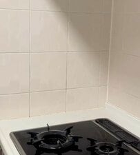 キッチンの白い壁にキャラメル色の「タイル柄シート」を貼るDIYアイデア。貼るだけの手軽さで、空間を海外風のおしゃれな雰囲気にガラリと変える実用的なリメイク術