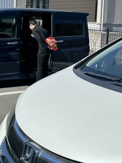 背中に花束を隠す息子さん