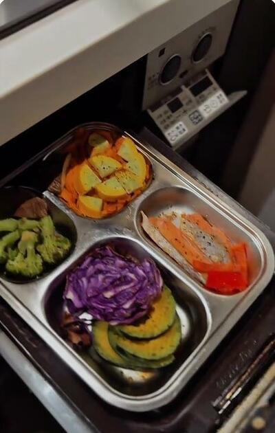グリルから引き出された、焼き上がった野菜と鮭のトレー