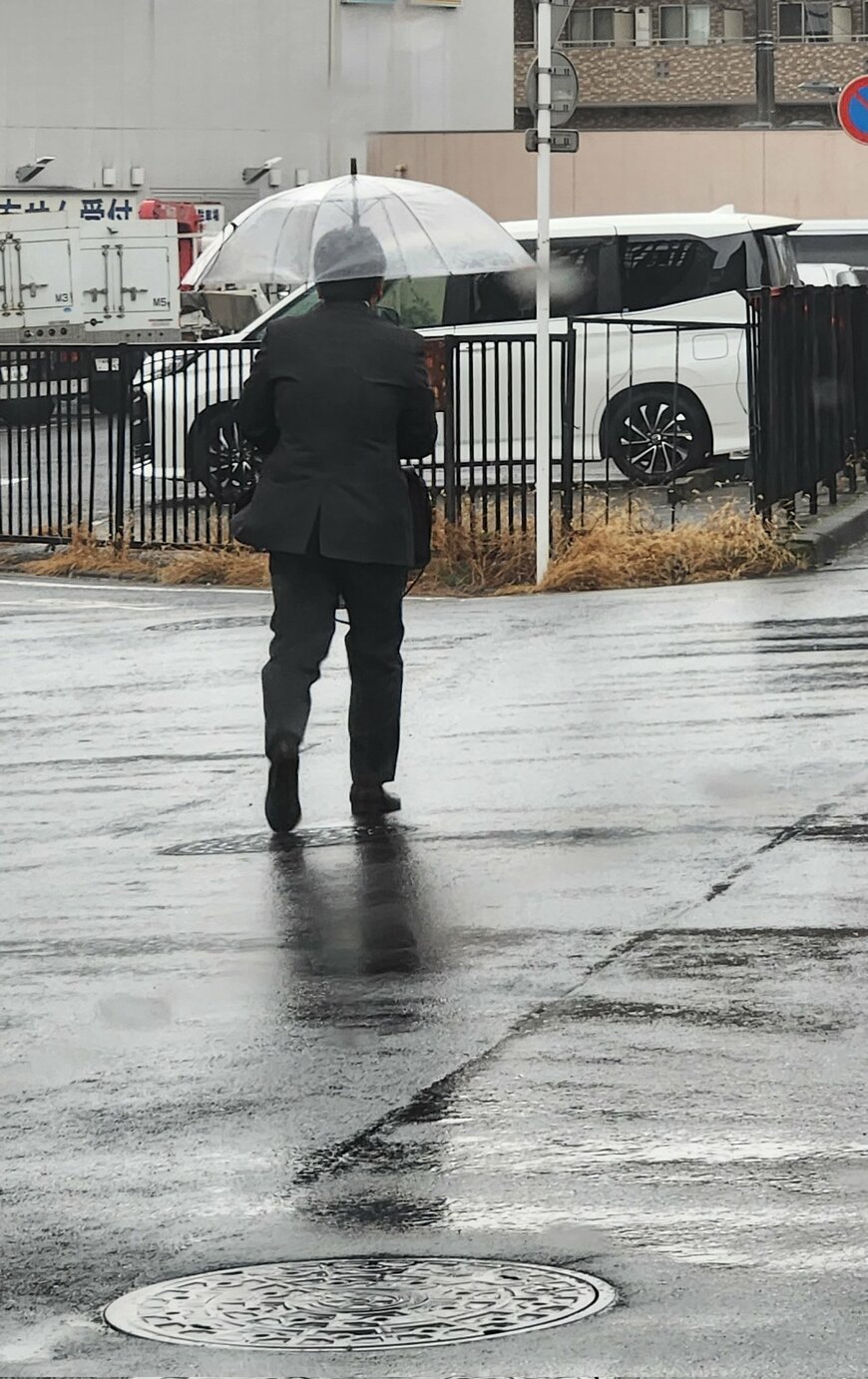 雨の中を歩くスーツ姿の男性