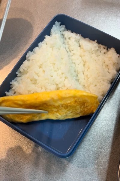 ご飯を詰めたお弁当箱に仕切りとして卵焼きを入れます